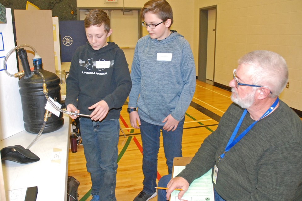 River Valley School science fair judge Mike Kapiczowski listens on Thursday, Jan. 30 as Grade 7 students Austin Fuchko, left, and Austin Nixon explain how they used an airtight anaerobic digester to determine whether manure or compost had a higher potential to create energy. 
Simon Ducatel/MVP Staff