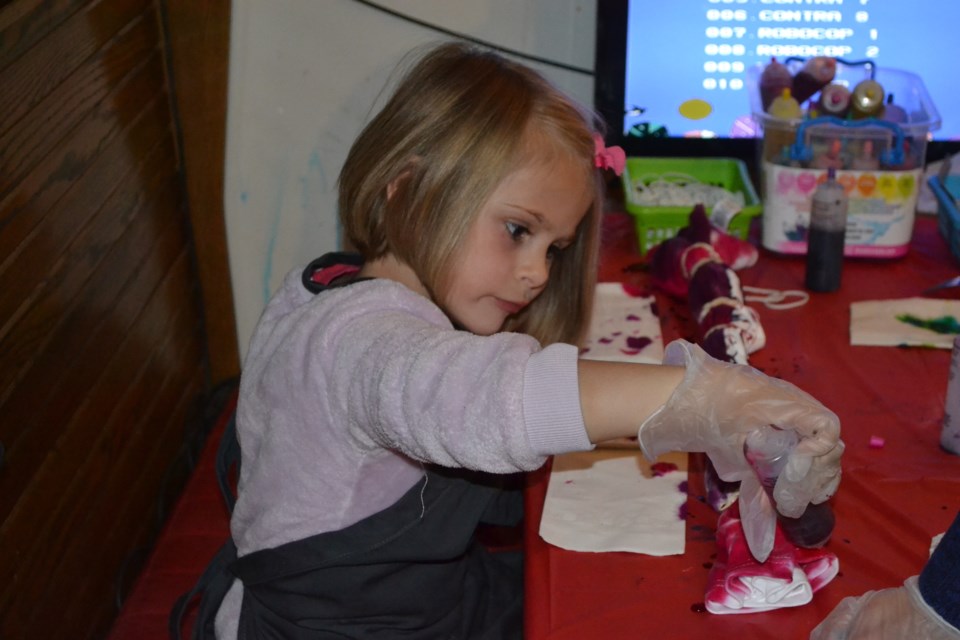 Dayn Nisbet, 4, carefully applies dye to the t-shirt she is working on. As part of its fundraiser on Friday night, Tracks Pub held a tie-dying session.
