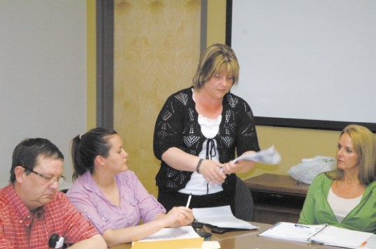 Monica St. Dennis, centre, hands out copies of a new business survey questionnaire during last week&#8217;s chamber meeting.