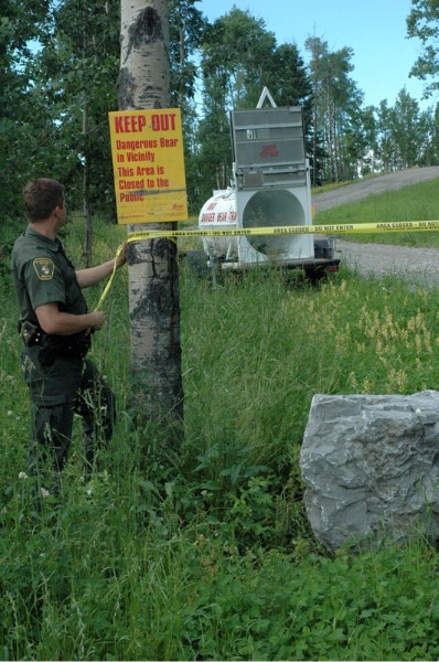 Fish and Wildlife officer Mark Hoskin marks off the area immediately around a bear trap set up on Snake Hill Monday. &#8211; Kim Comfort/Round Up