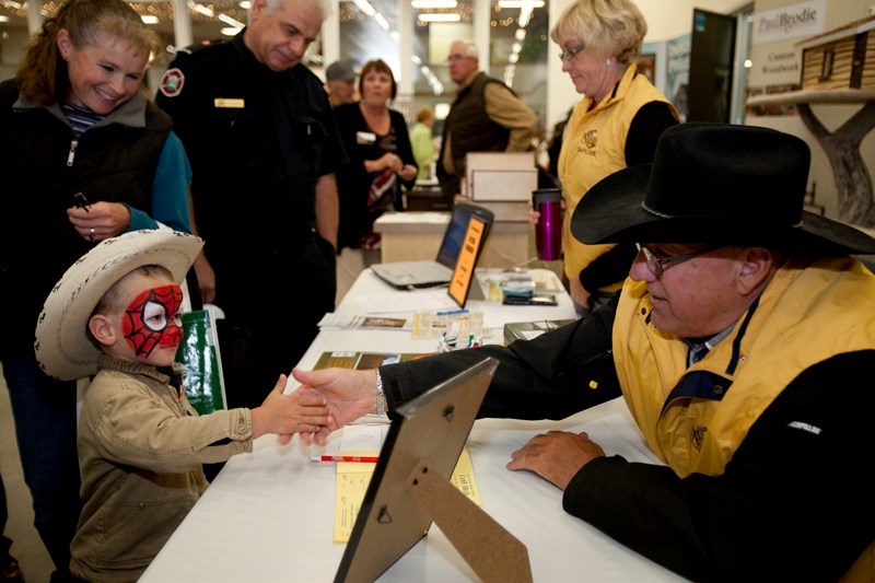 Jim Farn from the Sundre museum shakes hands with a boy at the business trade fair part of Neighbour&#8217;s Day 2011.