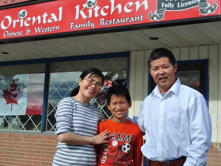 Joseph Shi, right, is pictured with his wife Christina and their adopted son Joshua outside of their restaurant in Cremona on Sept. 29.,