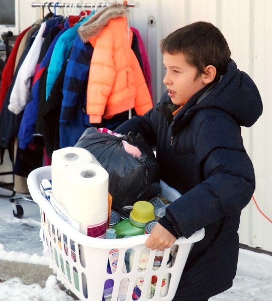 Kirby Werdal, 10, helps load up hampers prepared by Sundre Santa&#8217;s Anonymous volunteers at the former town office next to the fire hall on Friday, Dec. 18. He was among 