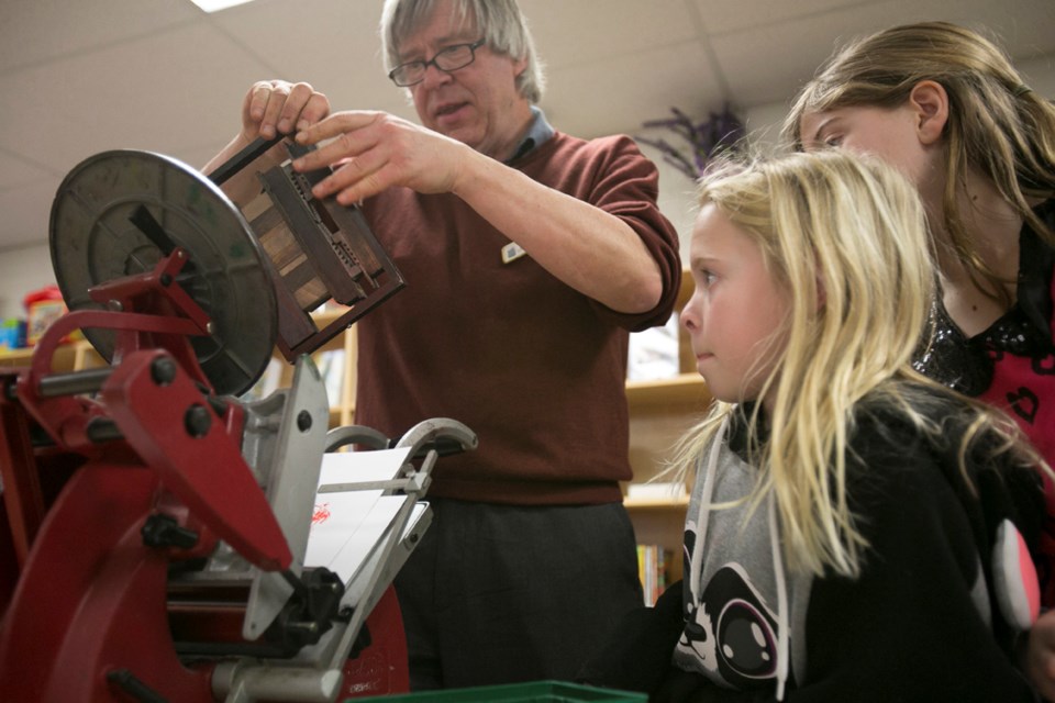 LITERACY DAY ACTIVITIES ó Sundre Municipal Library manager Jamie Syer helps Baileigh Bunch make a unique piece of art on a printing press as Abbie Messervey, right, waits for 