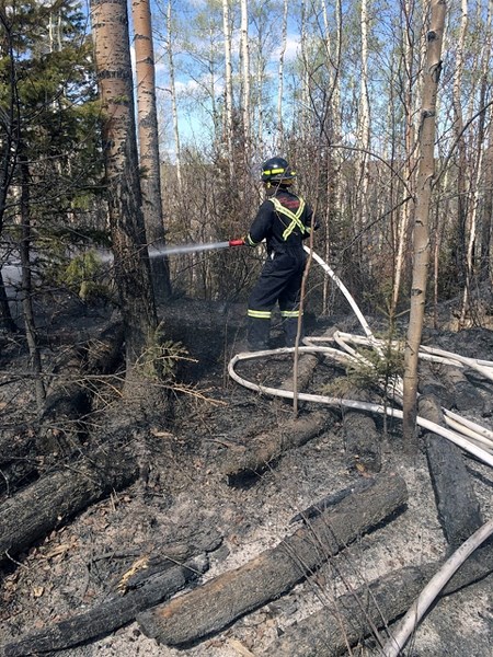 An Innisfail-area firefighter with OP Fire &#038; Safety battles a hot spot in the Fort McMurray area. The local company&#8217;s four firefighters in the northern area were