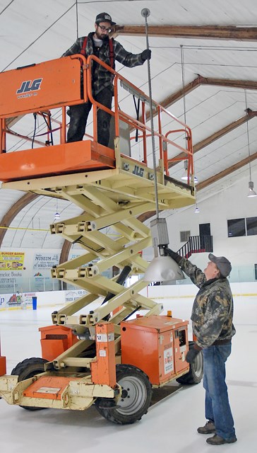 Jeff Correa, a subcontractor from Calgary, hands down an old light that was replaced with newer, brighter and more energy efficient LED lights to Sundre resident and business 