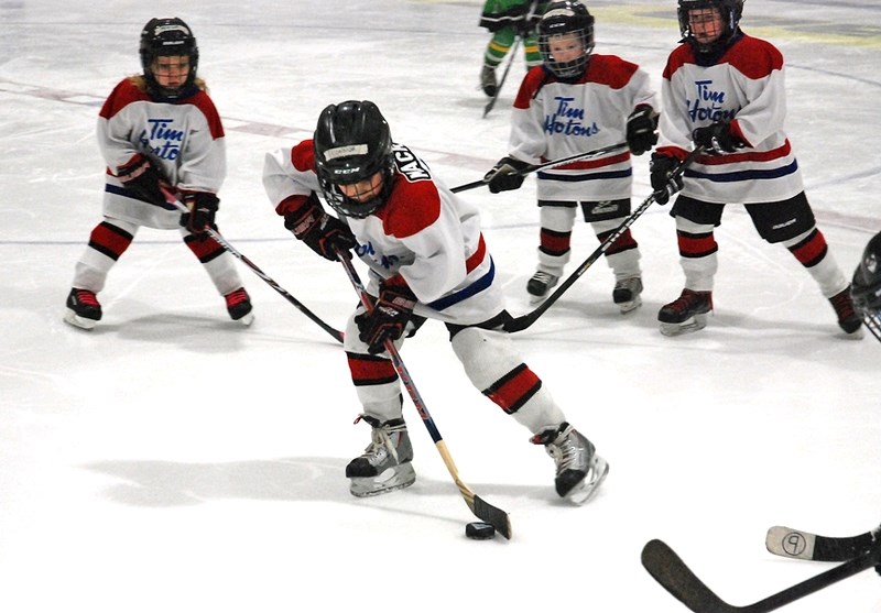 From left, Sundre Huskies tykes Connor Mackenzie, Trippett Lunde and Rhett Bartholow skate past their team&#8217;s bench for some high-fives in celebration of a goal.