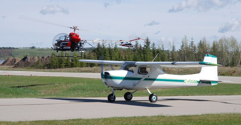 A civilian version of the helicopter flown in the television show M*A*S*H comes in for a landing alongside a plane. Glenn Chong, the helicopter&#8217;s pilot, flew out from