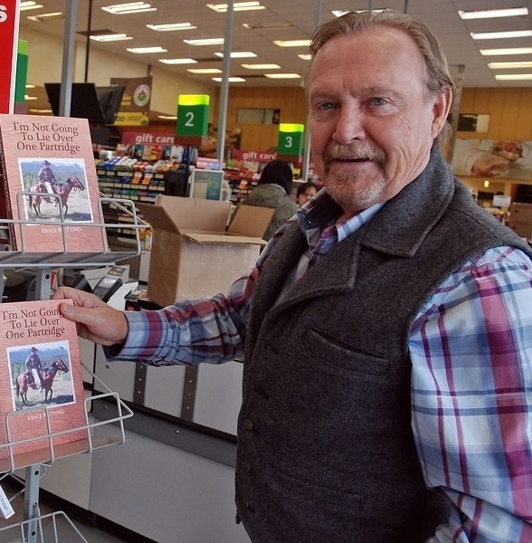 Sundre-area resident Ernie Nutting stacks numerous copies of his first book, I&#8217;m Not Going To Lie Over One Partridge, on a rack at the local IGA. The collection of