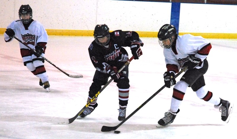 Sundre peewee Huskies player Evan Leasak scoops the puck away from the Cochrane Rockies&#8217; captain during first period action on Friday, Dec. 11 during the opening game