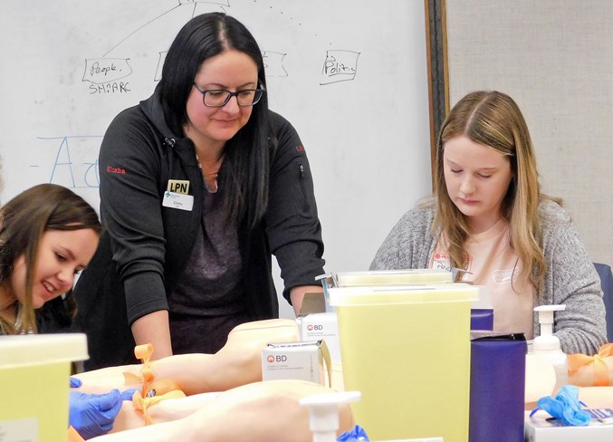  Sundre High School Grade 10 students Taylor Guzmanuk, left, and Presley Layden, right, learn how to administer an injection under the direction of a licensed practical nurse.