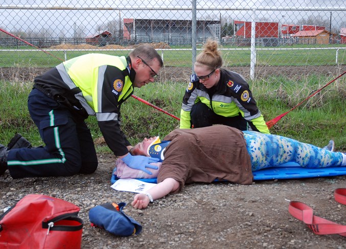  Primary care paramedics Clark Cochran, left, and Tara Riley “stabilize” Sundre High School Drama Club student Kacey Sewepegaham, who played one of several casualties in the staged crash scenario.