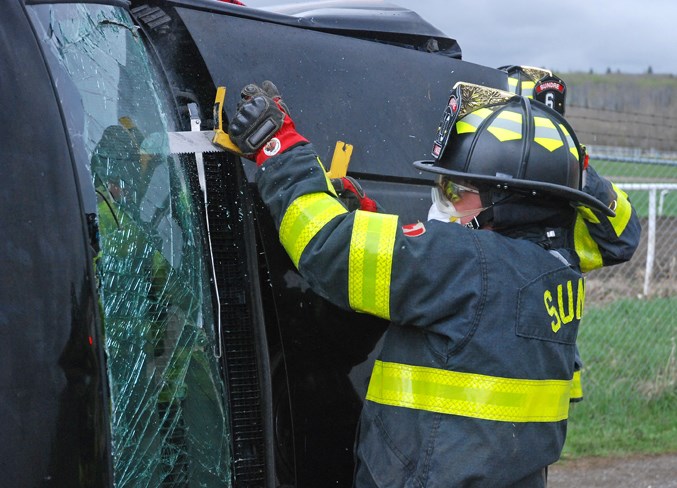  Bits of glass fly out as Lt. Dean Hass saws through the windshield of a crashed vehicle that rolled on its side with the driver “trapped” inside.