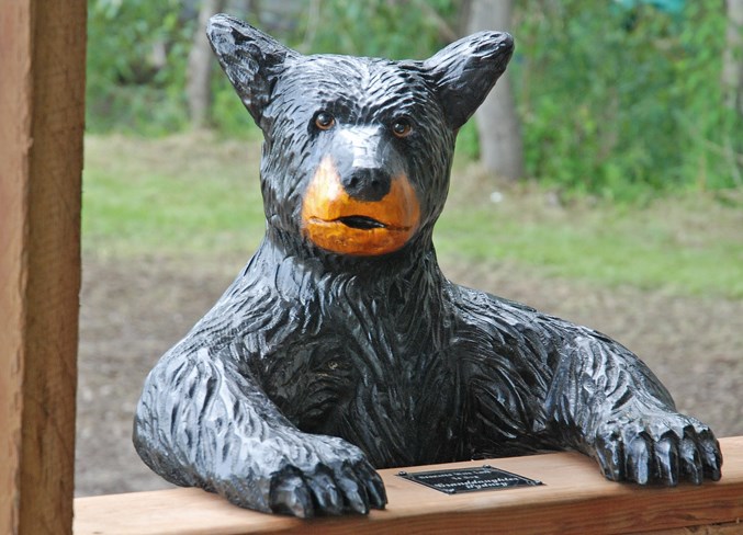  One of several wood carved black bears, which were created by Cochrane artisan Brian Widahl, peeks into the gazebo.