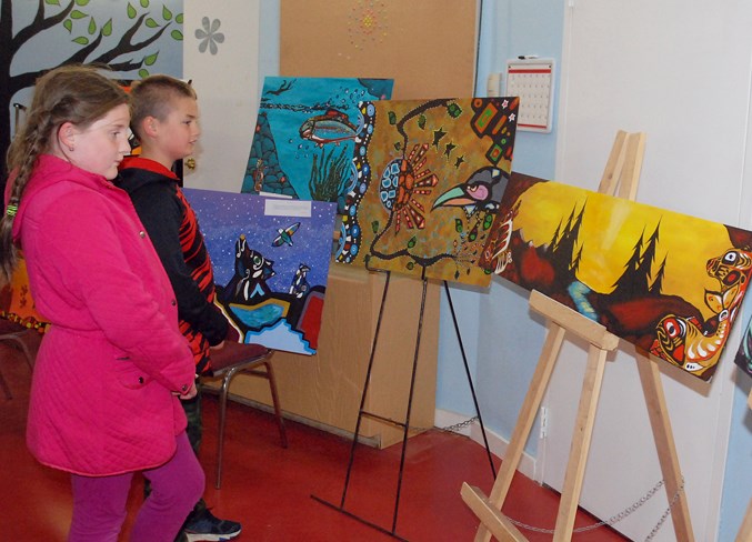  River Valley School Grade 3 students Annalea Long and Drake Weatherbee check out a number of paintings created by Sundre High School students in celebration of National Indigenous Peoples Day. The horizontal piece to the right depicting a golden sunset with silhouetted pine trees flanked by spirit animals was created by Art 20 student Cassandra Kopp. For her effort, she won an Indigenous art contest hosted by the Sundre and District Museum.