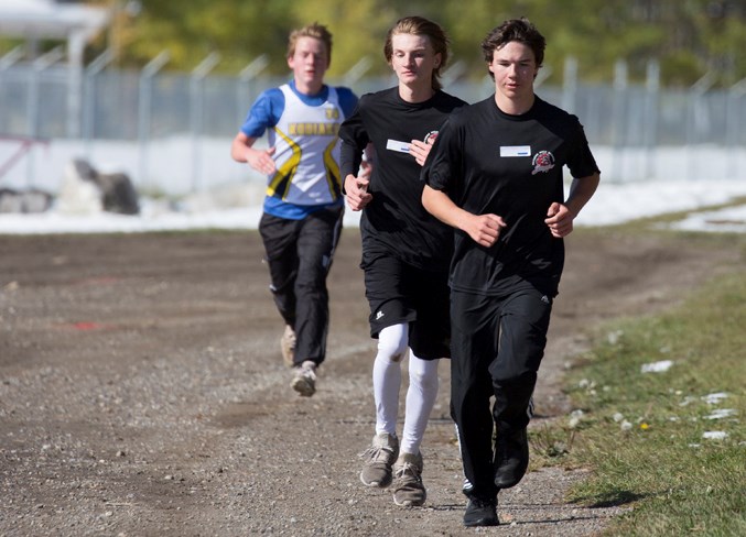  Sundre High School students Koby Smith, middle, and Quintin Ross run nearly neck and neck along a road at the base of Snake Hill during cross country divisionals on Oct. 1.