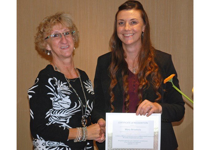  Chantal Crawford, right, a clinical nurse educator at the Sundre hospital as well as a director for the health professionals recruitment and retention committee, presents Mary Brisebois with 30-year service award during a ceremony for health-care staff who have reached major career milestones.