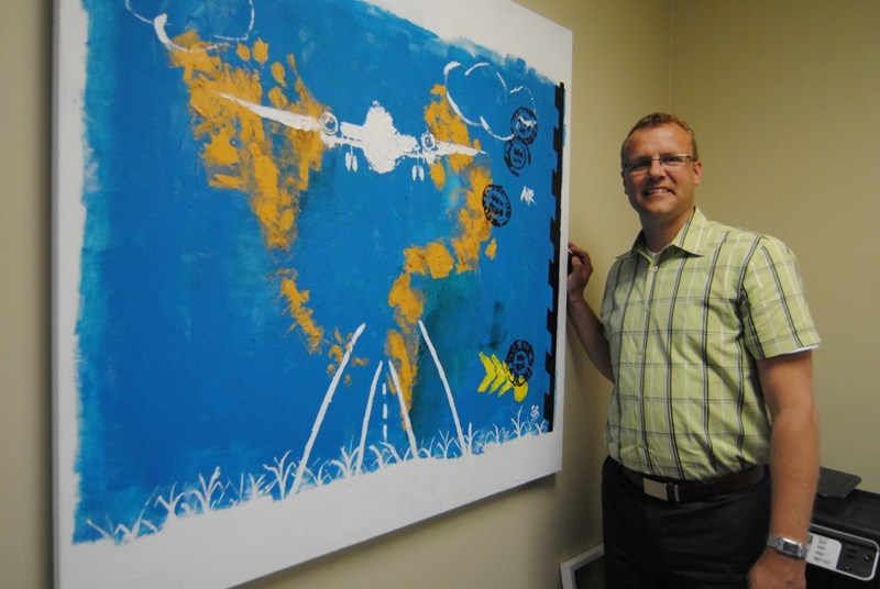 Steenstra standing in front of a painting created by his wife