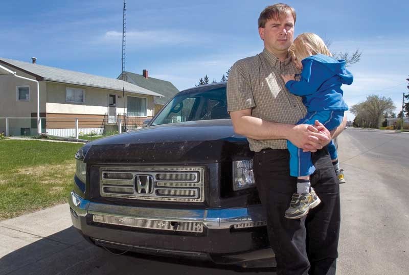 Gordon Wolters holds his son Friedrich, 3, by their truck, one of the things they managed to save before their house burnt down just outside of Slave Lake.