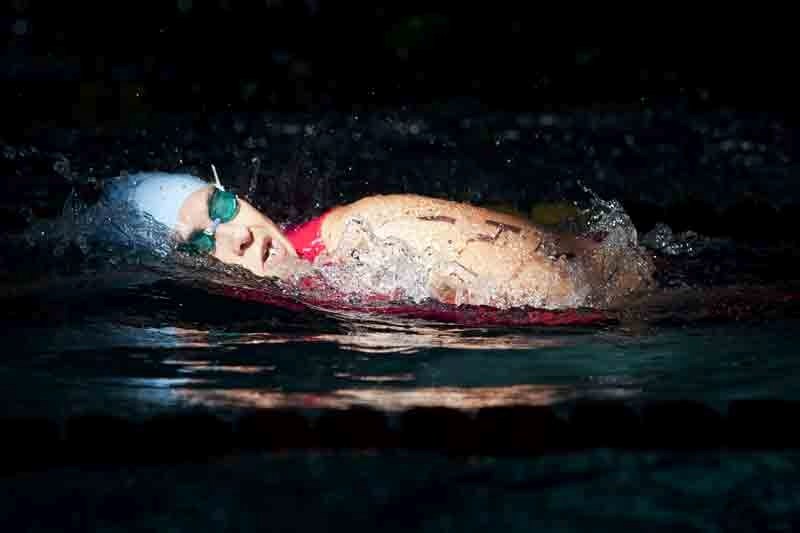 A competitor passes under a shaft of light coming from a skylight in the Innisfail Aquatic Centre during the swimming section of the Innisfail Triathlon last Saturday.