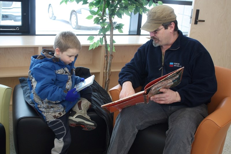 Don Allen reads a story to Neal Ziegler-Allen in the children&#8217;s section of the Innisfail Public Library. The library re-opened in its new location on Jan. 23.