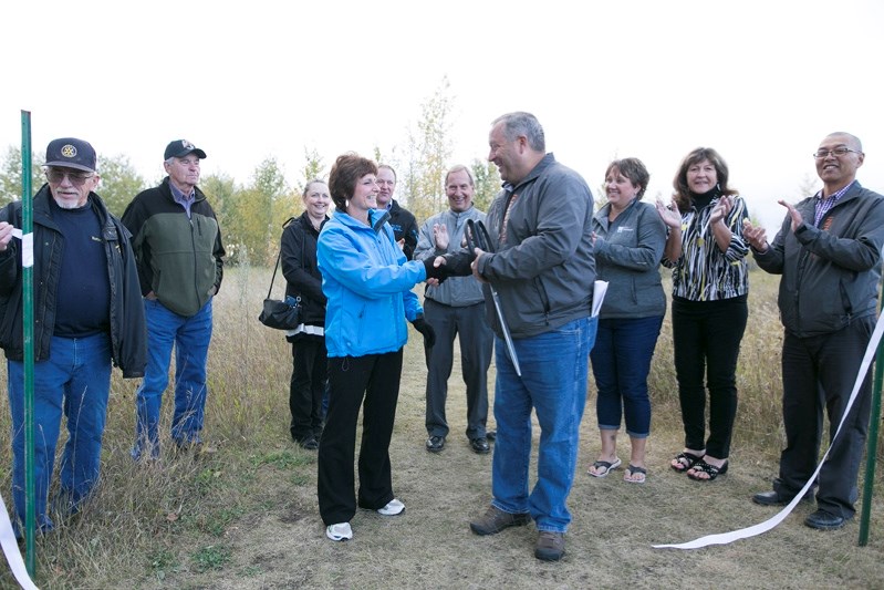 Heather Kirkham, president of the Rotary Club of Innisfail, and Mayor Brian Spiller shake hands during a ribbon-cutting ceremony for the enhanced Napoleon Lake Rotary Trail