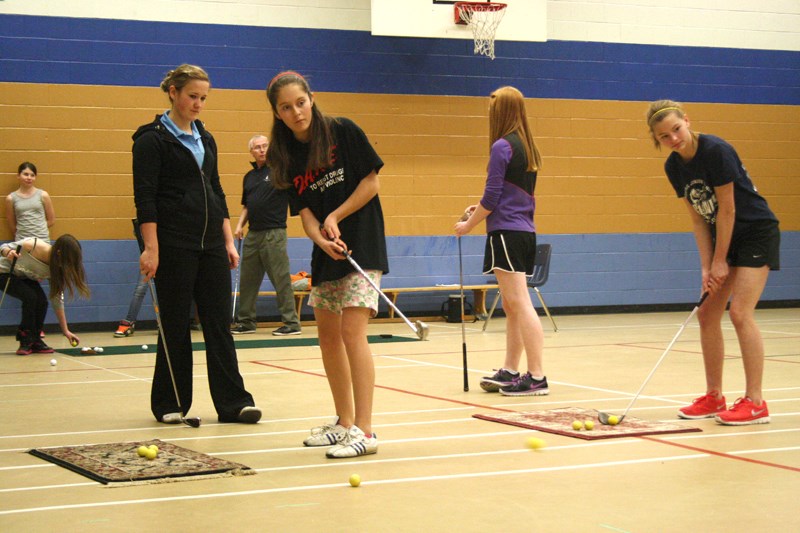 Shanice Ross, 14, gets golf tips from Melissa Koster, 21, during phy-ed class at Innisfail Jr./Sr. High School April 11.