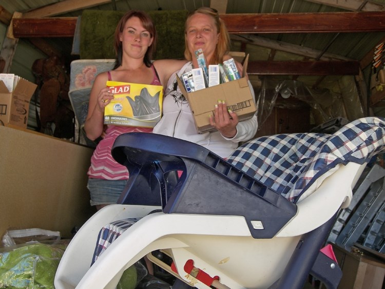 Nichole Harrison (left) and Jean Stewart display some of the donations, like garbage bags and toothbushes, received in their drive to help people trying to recover from the