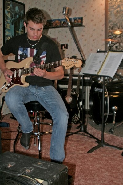 Devin Cooper poses with his guitar in a jam space in the basement of his home in Innisfail.