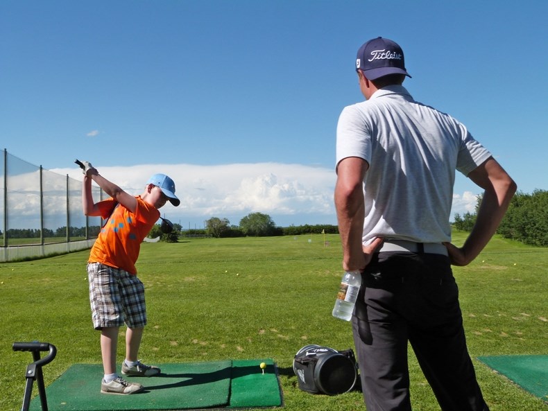 PGA Tour Canada Professional James Love watches Innisfail Junior golfer Ethan Meding&#8217;s backswing during the ATB Financial Junior Golf Clinic which took place at the