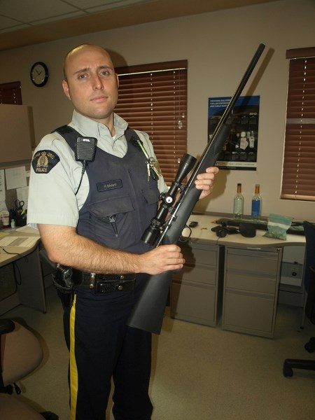 Innisfail RCMP Const. Pascal Bedard holds the rifle seized Aug. 15 during the arrests of a Red Deer youth gang on Penhold streets.