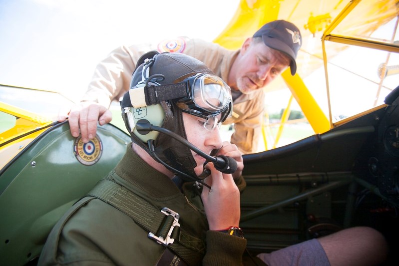 Vintage Wings pilot Christie Whelan helps cadet Theodore Magee get ready before his flight in a Boeing PT-27 Stearman at the Red Deer Airport on July 23.