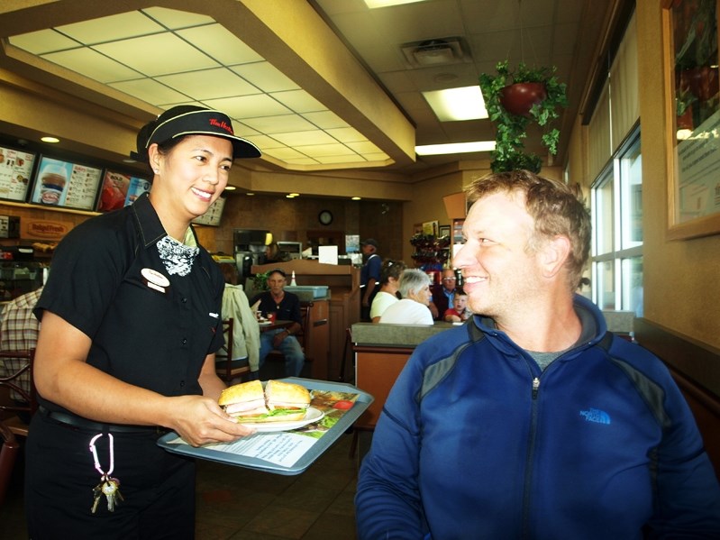 Christine Pasiliao, assistant manager at the Innisfail Tim Hortons, serves Dana Meise a free coffee and sandwich during his brief stop in Innisfail last week.