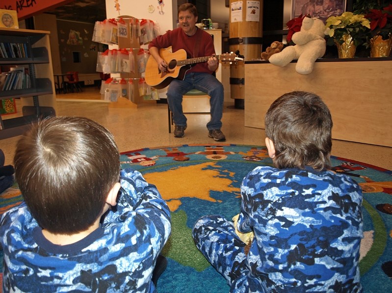 Zach McAmmond (left) and his older brother Ben listen to local musician Tom Lindl play at the annaul Twilight Teddy Tales event at the Innisfail Library on Dec. 12. The event 