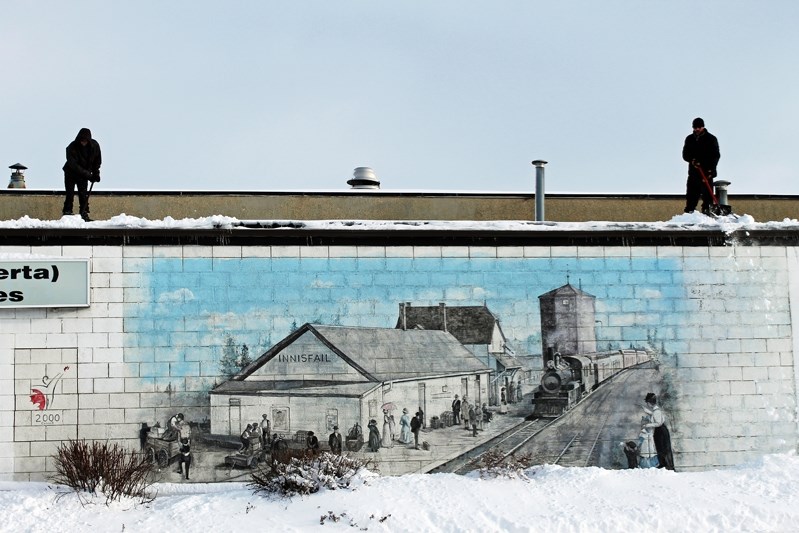 Workmen shovel snow off a downtown roof in Innisfail.