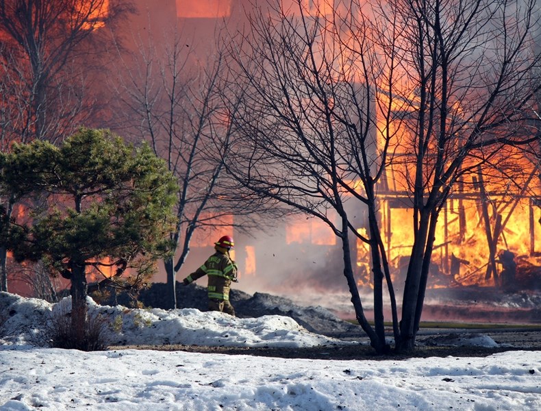 A Penhold firefighter walks by the fully engulfed Wild Rose Manor that was destroyed by a spectacular blaze on April 10.