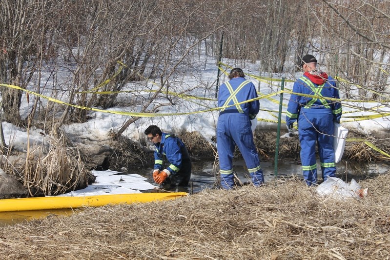 Innisfail town workers lay down absorbent pads onsite at the northeast corner of Dodds Lake where a hydrocarbon spill was reported on April 11.