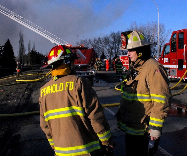 Penhold fire chief Jim Pendergast (right) speaks with a firefighter during the April 10 blaze at Wild Rose Manor in Penhold.
