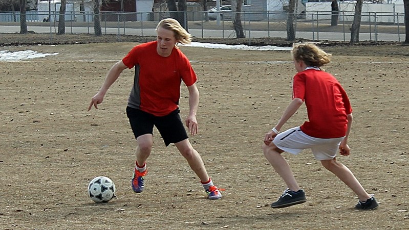 Simon Bigger ball handles around a team member during the first outdoor Innisfail United soccer practise on April 14.