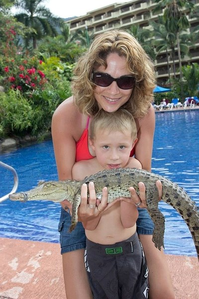 Kim Tucker cuddles Gage Daoust and a baby alligator on a recent family vacation. Gage is fighting for his life at Edmonton&#8217;s Stollery Children&#8217;s Hospital..