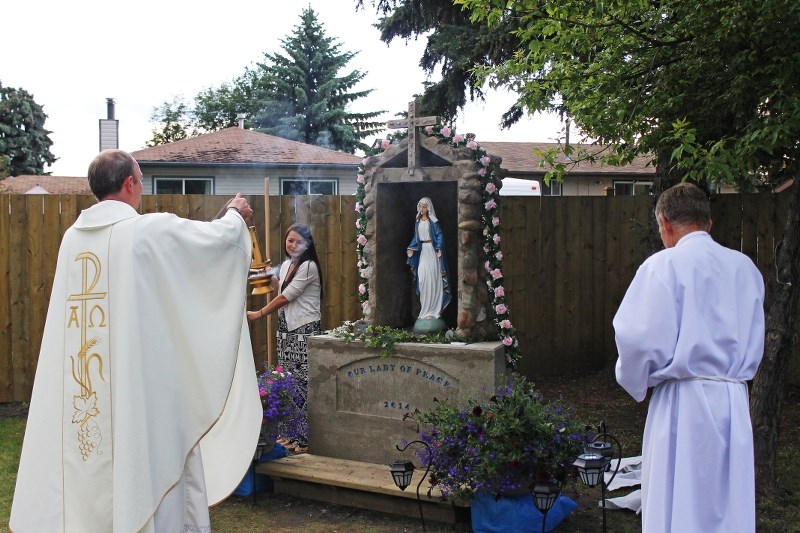 Our Lady of Peace pastor Father Tom Puslecki waves incense towards the grotto dedicated to Mary during the dedication service On June 20.