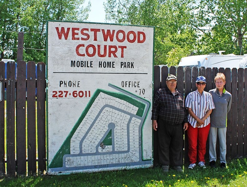 Westwood Court Mobile Home Park residents Ed Kaye (far left), Myrna Kissick (second from left), and Karen Kaye pose beside the park sign in their neighbourhood they fear may