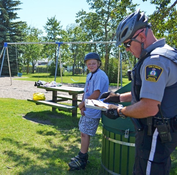 Brayden Laduke receives a positive ticket for wearing a helmet at the spray park near the Innisfail Aquatic Centre on July 29.