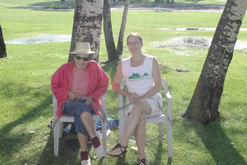 90-year-old Isabelle Roberts and grand-daughter Shaun Pears wrap a logging chain around themselves at Dodd&#8217;s Lake Manor to protest a surprise tree removal.