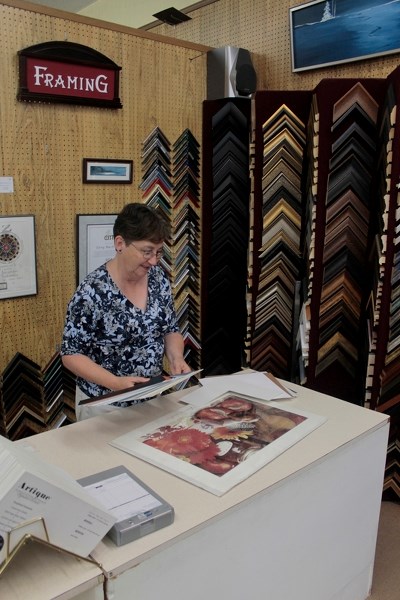 Carol Ritten Smith, owner of Studio Arts, sizes up a mat for a print.