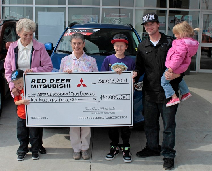 Carole Sim (far left) of the Innisfail and District Food Bank and Marian Moritz of the Innisfail Christmas Bureau (second from left) both receive a cheque from Red Deer