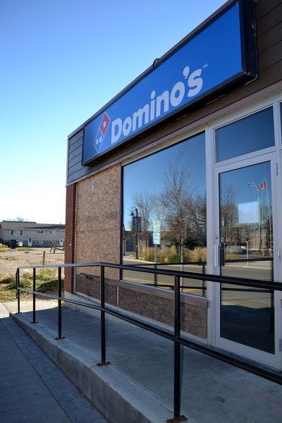 A large front window of Domino&#8217;s Pizza has been boarded up since the arson fire on Oct. 19.
