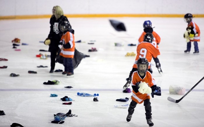 Volunteers collect items from the annual Stuffy, Toque, or Mitt Toss on Nov. 27 at the Innisfail Arena after the first goal was scored during the game between the Innisfail