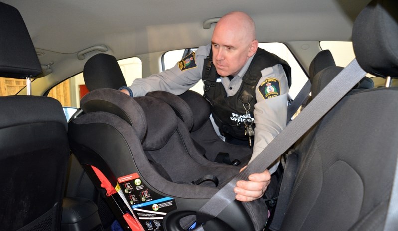 Innisfail community peace officer Ryan Anderson inspects a car seat during a recent car seat safety clinic in Innisfail.