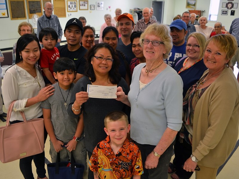 Grace Gresos, chair of the Phil-Can Neighbourhood Association of Innisfail (centre-left), presents May French, president of the Innisfail Seniors Drop-In Centre, a cheque for 